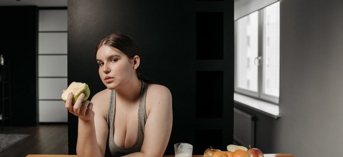 Woman enjoying an apple and glass of milk, promoting a healthy lifestyle indoors.