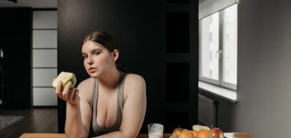 Woman enjoying an apple and glass of milk, promoting a healthy lifestyle indoors.