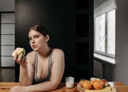 Woman enjoying an apple and glass of milk, promoting a healthy lifestyle indoors.