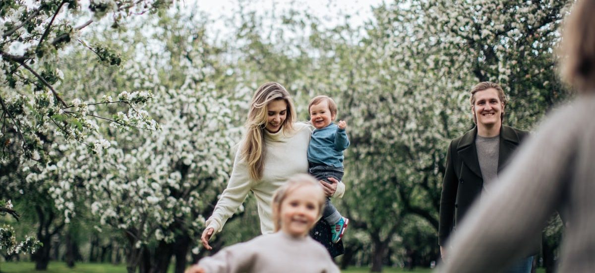 A joyful family enjoys a playful day outdoors amidst blossoming trees in spring.