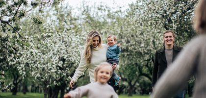 A joyful family enjoys a playful day outdoors amidst blossoming trees in spring.