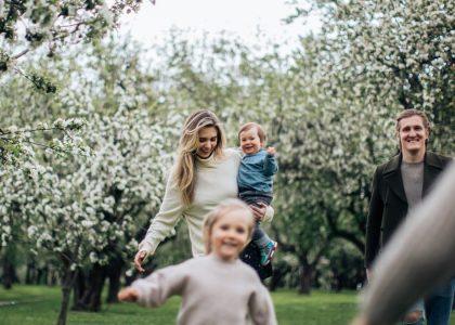A joyful family enjoys a playful day outdoors amidst blossoming trees in spring.