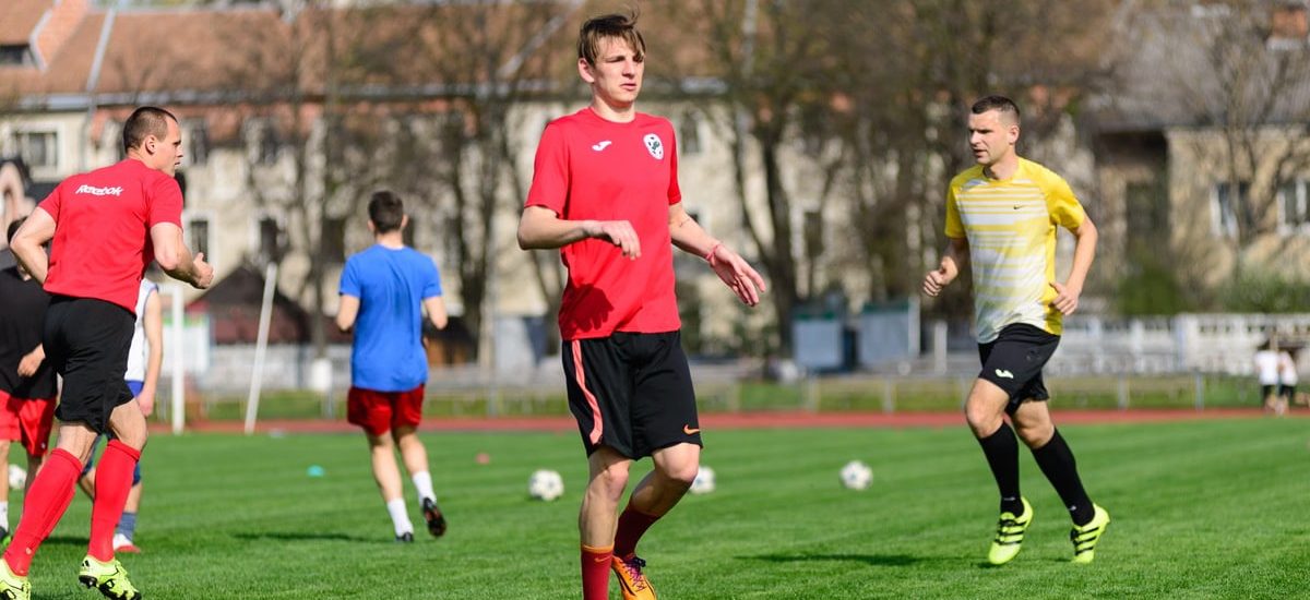 Young men practicing soccer on a sunny day at an outdoor field, focusing on exercise and teamwork.