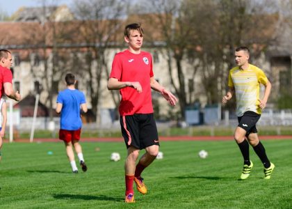 Young men practicing soccer on a sunny day at an outdoor field, focusing on exercise and teamwork.