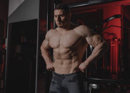 Shirtless bodybuilder flexing muscles under dramatic gym lighting. Fitness and strength.